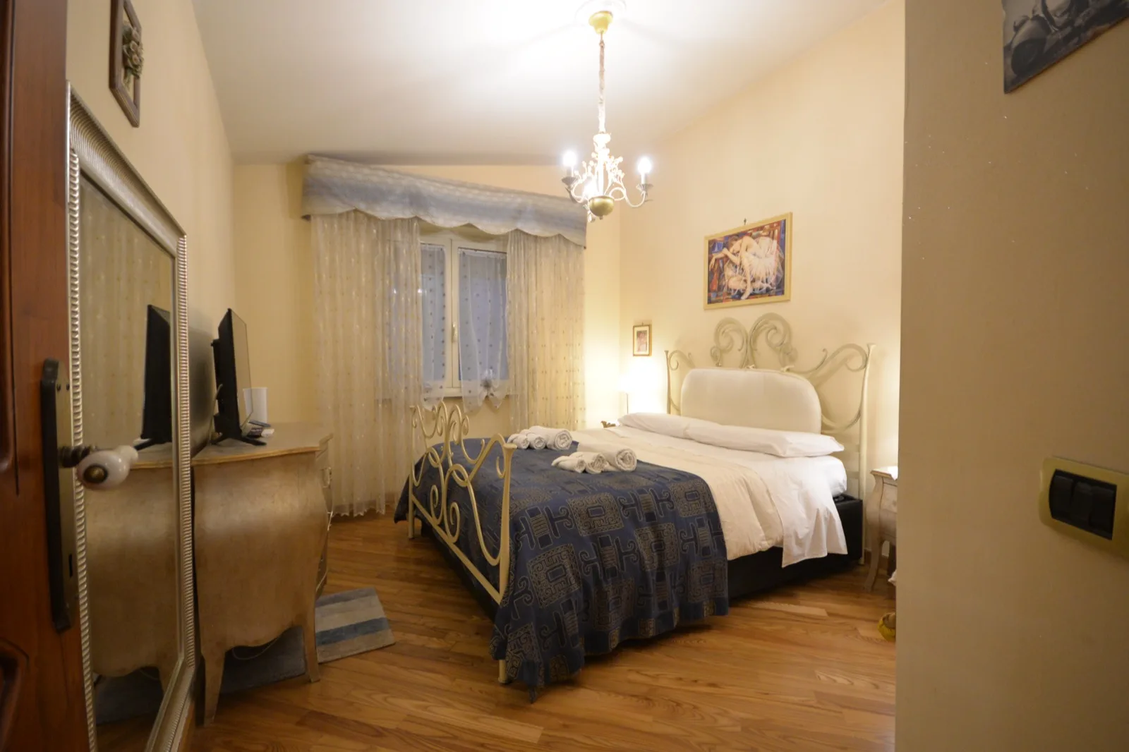 Vista d'insieme della camera matrimoniale con lampadario e ampio armadio
