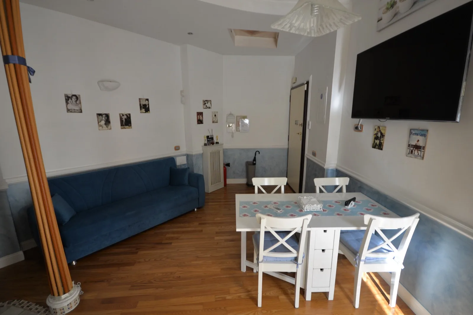 Zona giorno open space con divano blu, tavolo da pranzo e Smart TV